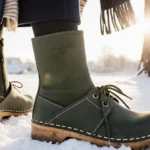 Woman stands confidently wearing Steve Madden clogs with navy coat and scarf near snow-covered tree