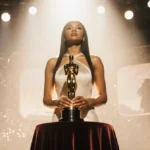Teyana Taylor holding her Golden Globe trophy with the award stage glowing behind her