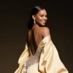 Teyana Taylor posing confidently in a diamond-encrusted Schiaparelli gown with flowing train and golden lighting highlighting
