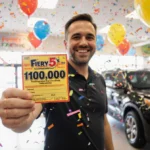 Thomas McCawley celebrating his lottery win with $100000 ticket and colorful balloons in festive store