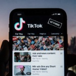 Dimly lit smartphone screen showing TikTok feed with ads and distorted logo and out-of-order stamp