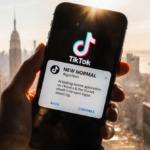 Hand holding smartphone showing TikTok notification NEW NORMAL with warm golden glow over blurred cityscape