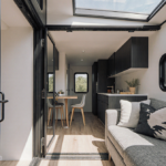 Tiny home revealing spacious interior with sofa and floor-to-ceiling window with natural light from skylight