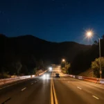 Cars drive along reopened Topanga Canyon Boulevard with streetlights illuminating the road and canyon hills rising under star