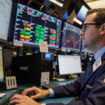 Trader hovering over keyboard with Bitcoin ticker flashing $87,000-$89,000 and oil and Fed rate updates on trading screens