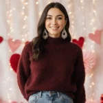 Woman poses in cozy burgundy sweater with jeans and Amazon accessories under soft Valentine