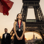 Victoria Beckham standing with her back to the Eiffel Tower at sunset with a fluttering red and black French flag.