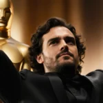 Wagner Moura celebrating with arms raised and Golden Globe award in hand with elegant attire and golden background