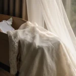 A white wedding dress drapes over a wooden coffin with a baby