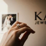 Woman holding diamond wedding ring with soft light and blurred wedding photo on wall