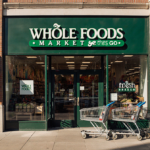 Abandoned shopping carts arranged neatly by door with Whole Foods sign partially visible above Amazon Go façade and warm natu