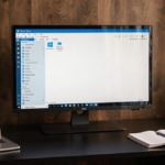 Monitor displaying Windows 11 desktop with clean taskbar and warm natural light.